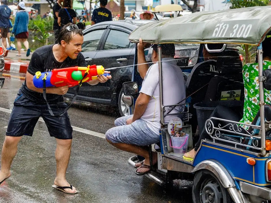 A man fires a large water gun at tuk-tuk passengers on the wet moat road in Chiang Mai during Songkran