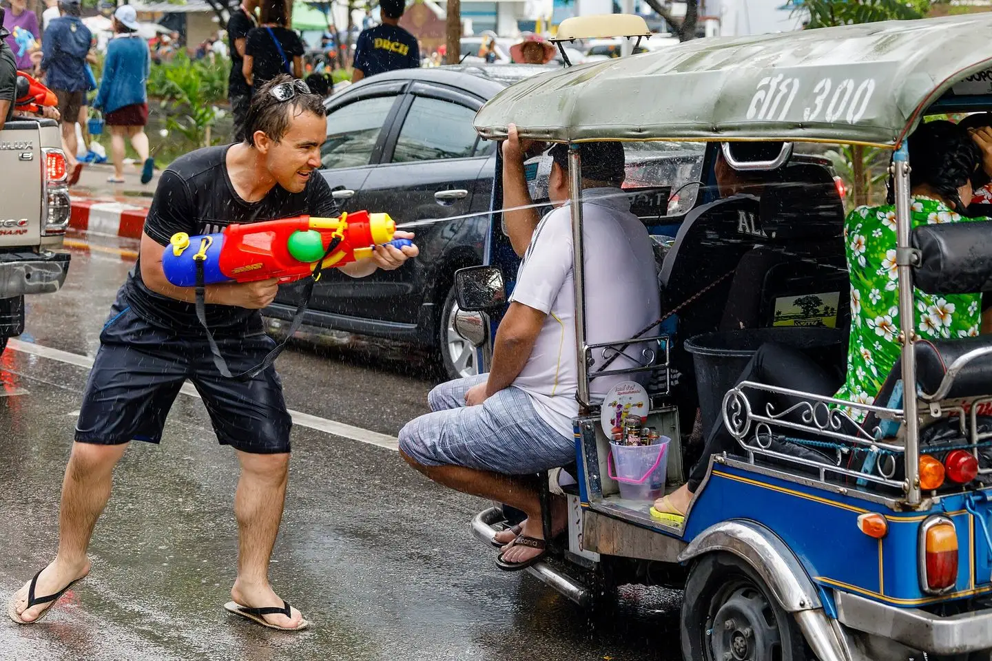 A man fires a large water gun at tuk-tuk passengers on the wet moat road in Chiang Mai during Songkran