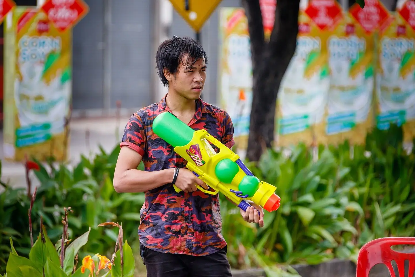 A young man in a floral shirt holding a large pump-action water gun during Songkran in Chiang Mai