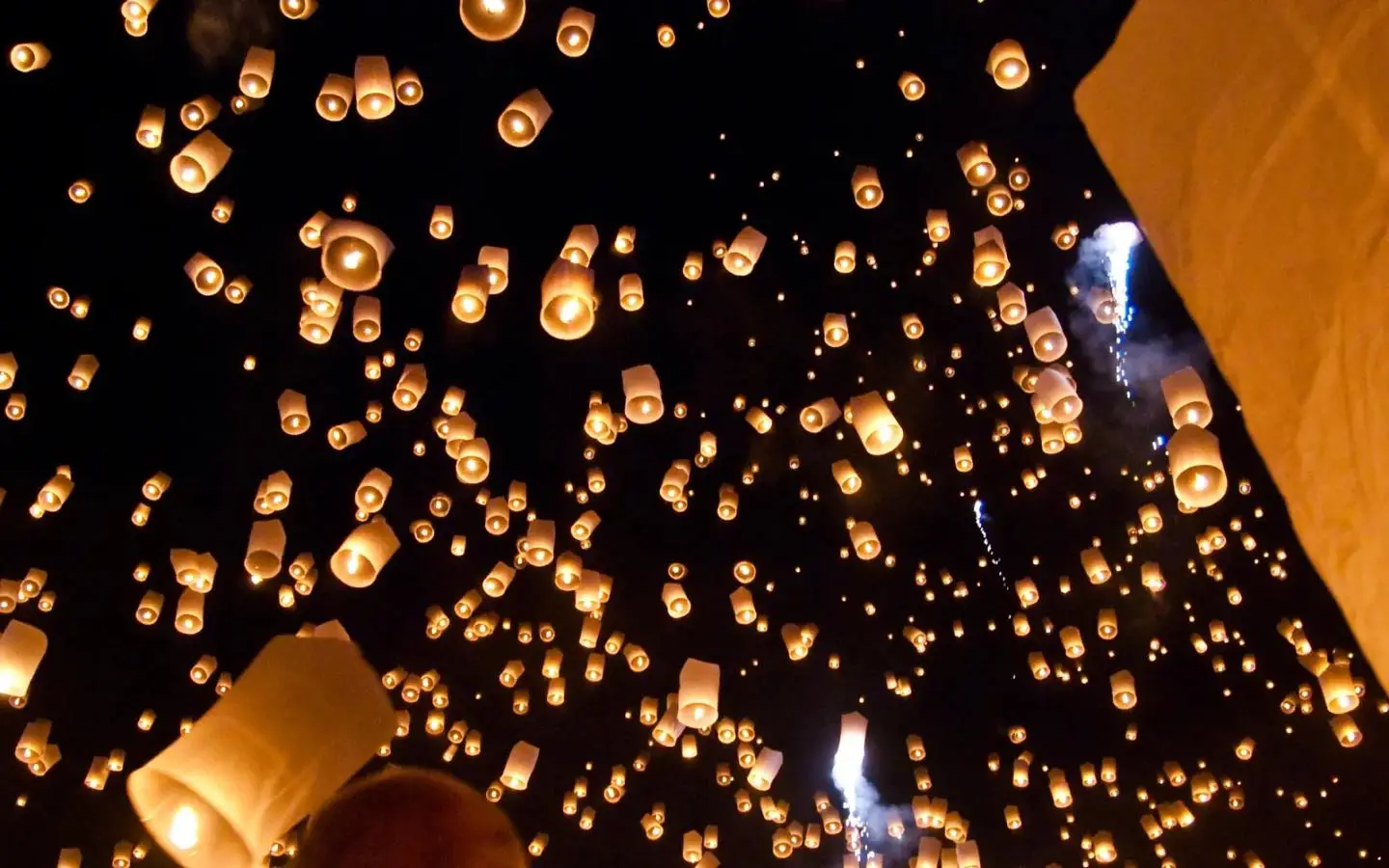 Thousands of sky lanterns rising into the night sky at a Yi Peng mass release