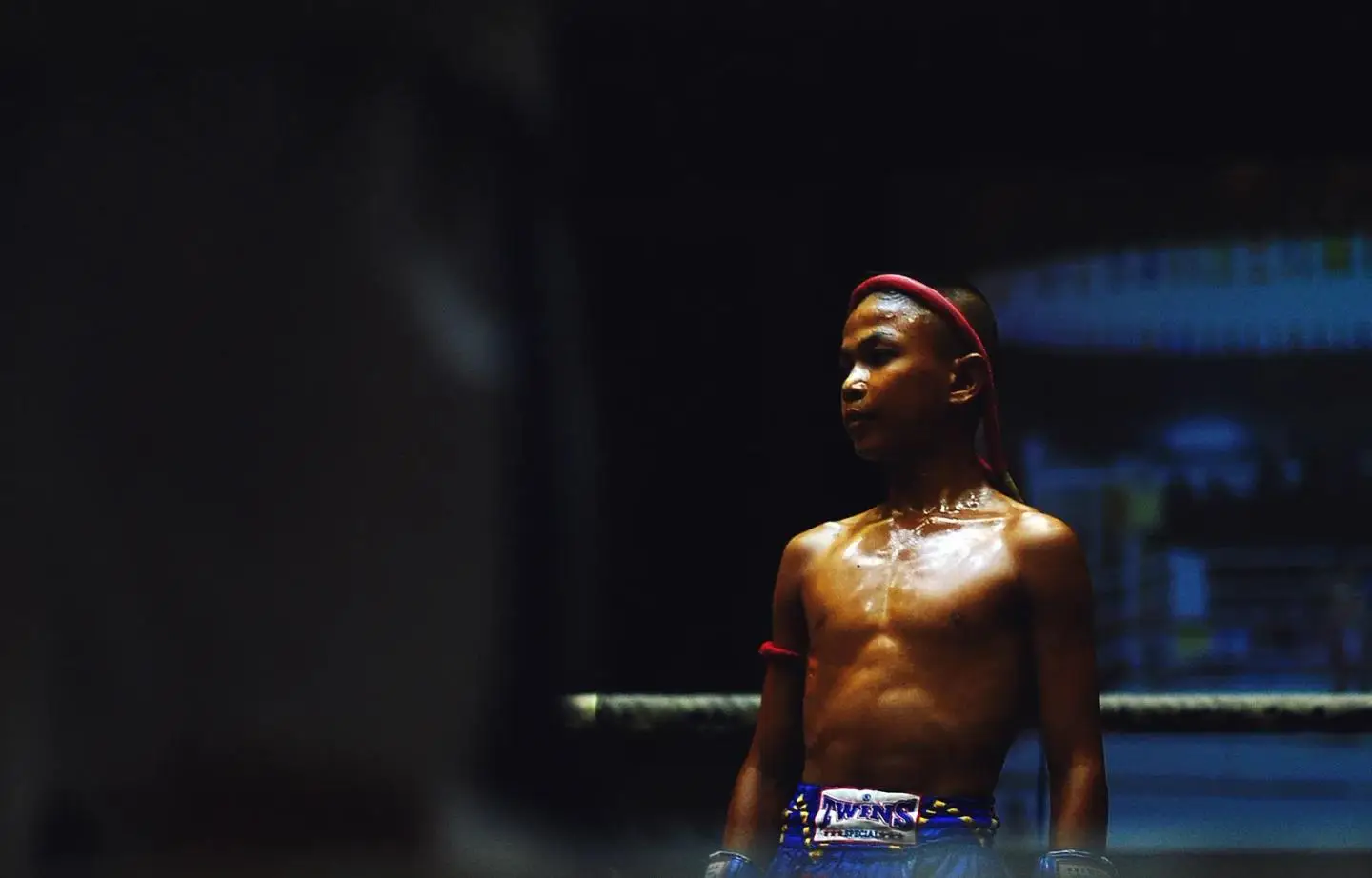 A young muay thai fighter in the ring wearing a mongkol